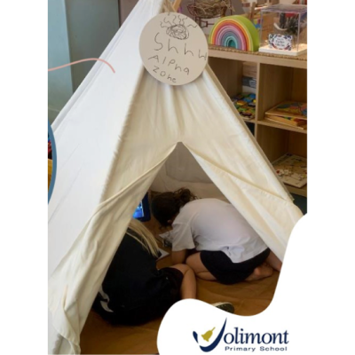An image of two students inside a small tent with a sign on the top saying 'Sssh! Alpha zone in progress!' from Jolimont