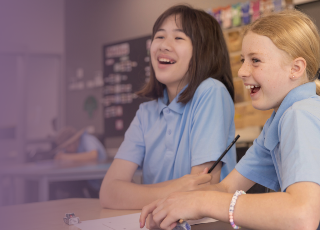 Happy, engaged students laughing in the classroom while writing